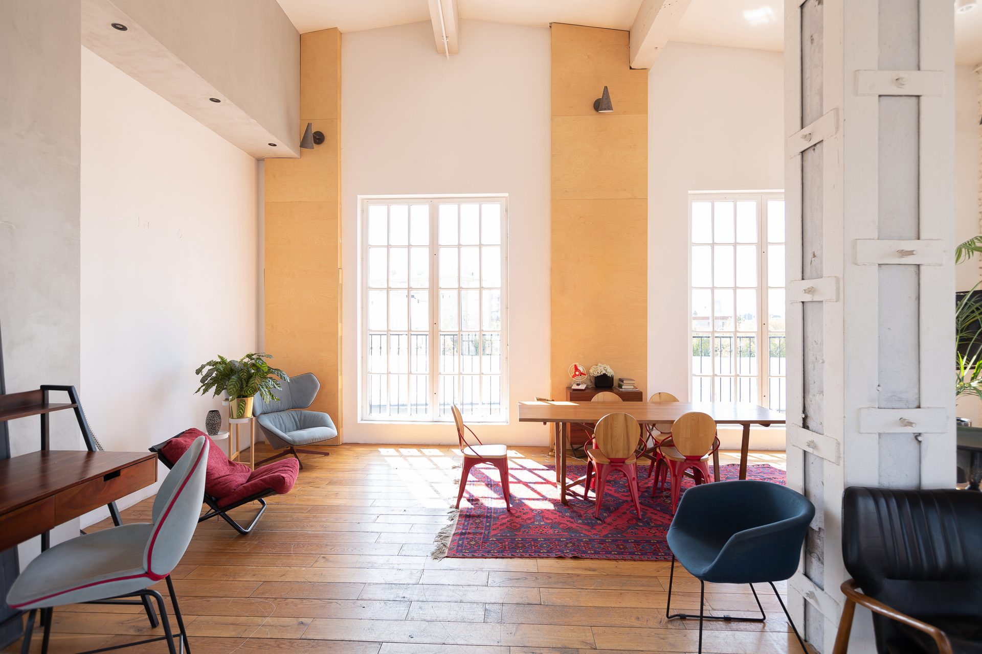 modern-design-of-a-huge-white-bright-room-with-two-red-sofas-and-many-large-windows-full-of-sunshine-high-ceiling-and-wooden-parquet